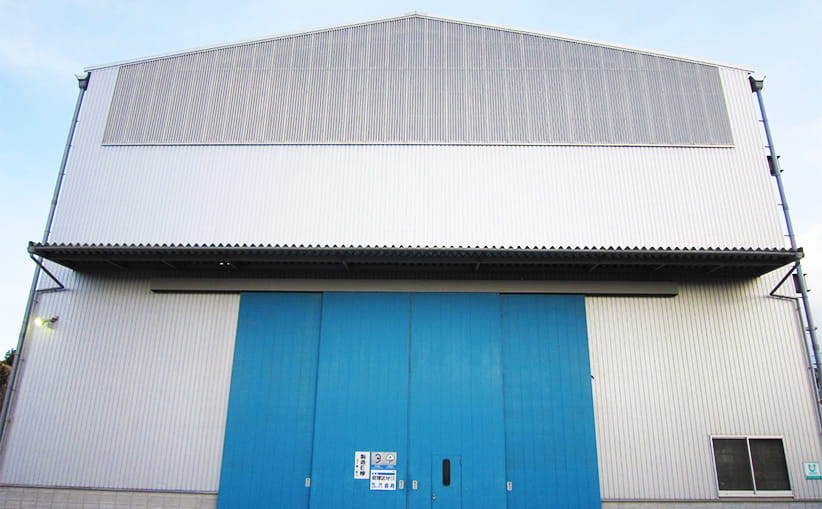 青い大きな扉が特徴的な、ガルバリウム鋼板を使用し建築した工場